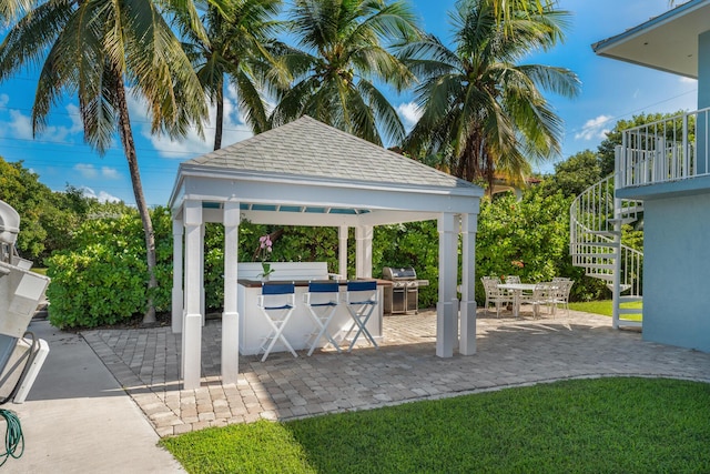 view of community featuring a gazebo, exterior kitchen, a bar, and a patio