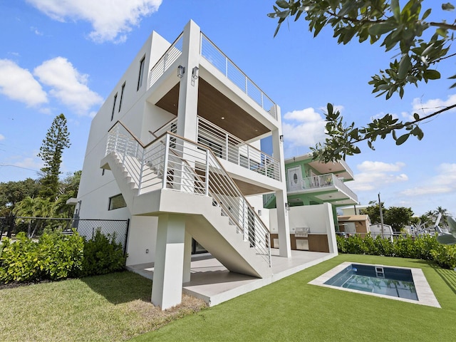 back of house featuring stairs, fence, a lawn, and stucco siding