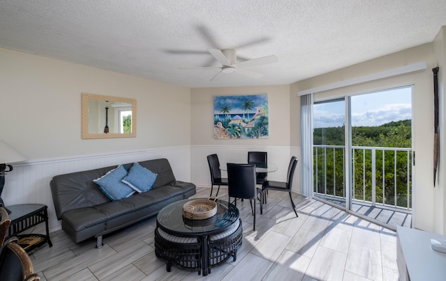 living room featuring ceiling fan and a textured ceiling