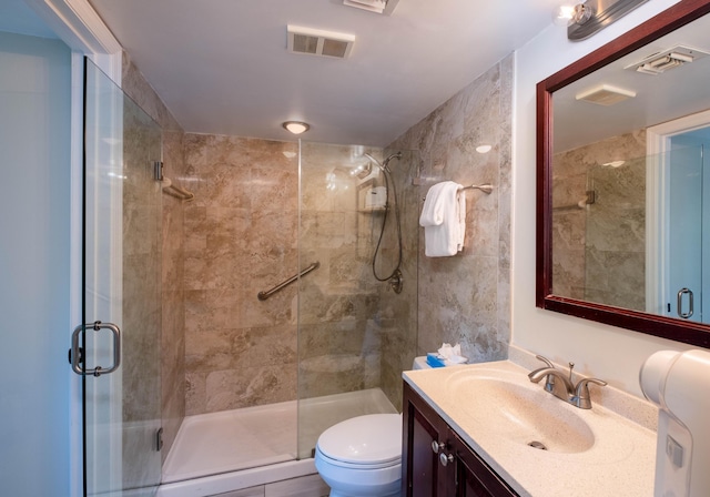 bathroom featuring a shower with door, vanity, and toilet