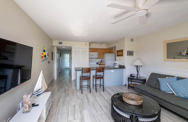 living room with ceiling fan and a textured ceiling