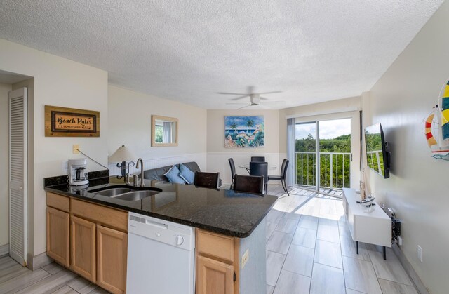 kitchen with sink, dark stone countertops, ceiling fan, white dishwasher, and a textured ceiling