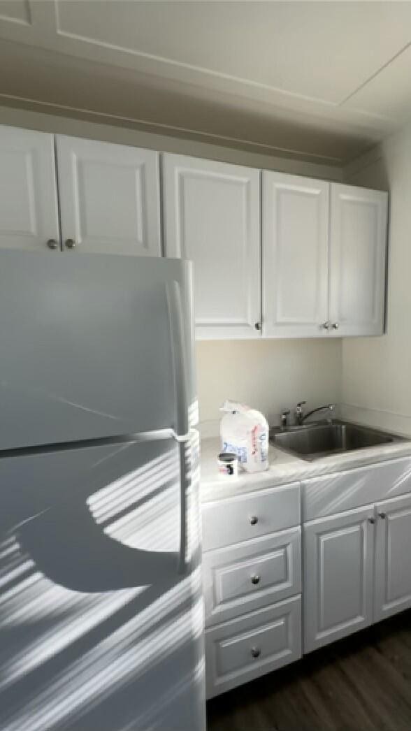 kitchen featuring dark hardwood / wood-style flooring, sink, white cabinets, and refrigerator