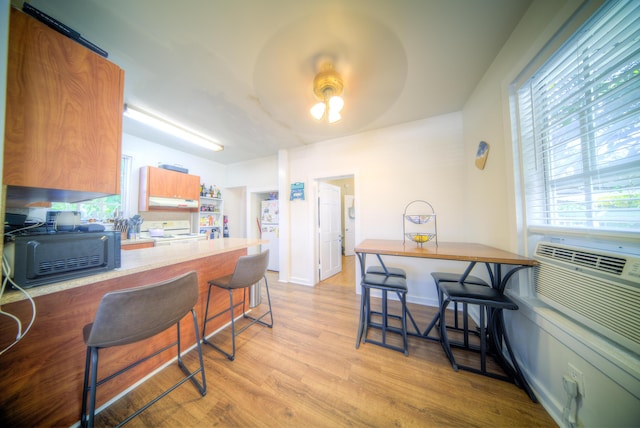 kitchen featuring light hardwood / wood-style flooring, a breakfast bar area, and white electric range oven