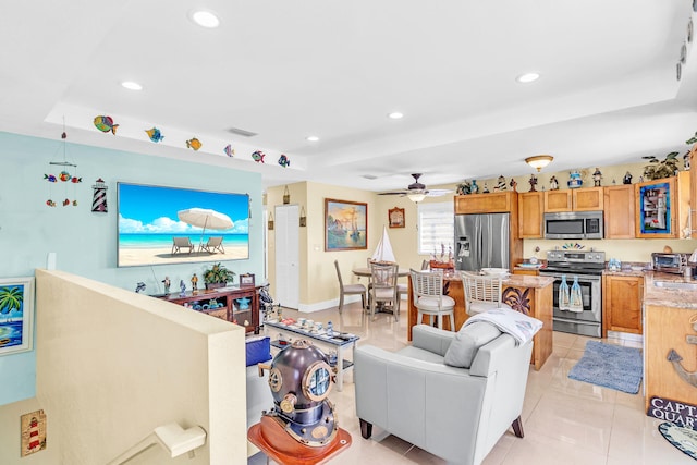 tiled living room with ceiling fan, a raised ceiling, and sink