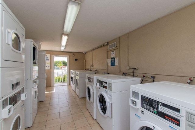 laundry room with stacked washer and clothes dryer, washing machine and dryer, and light tile patterned floors