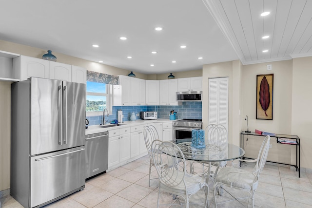 kitchen featuring sink, light tile patterned floors, white cabinetry, stainless steel appliances, and tasteful backsplash