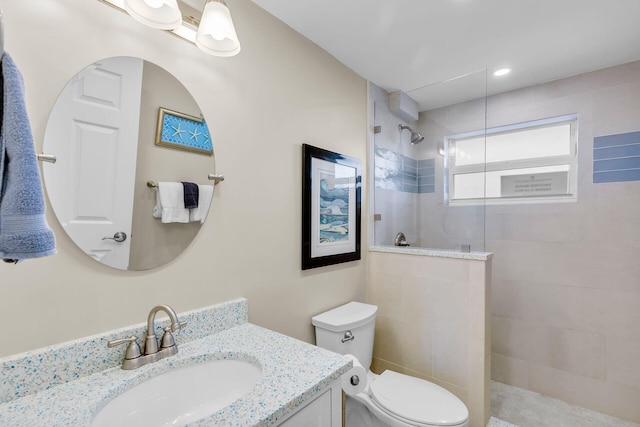 bathroom with vanity, toilet, and tiled shower