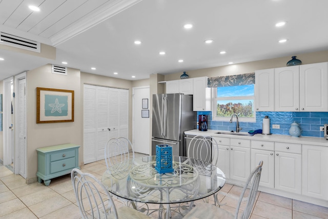 kitchen featuring stainless steel refrigerator, sink, decorative backsplash, and white cabinets