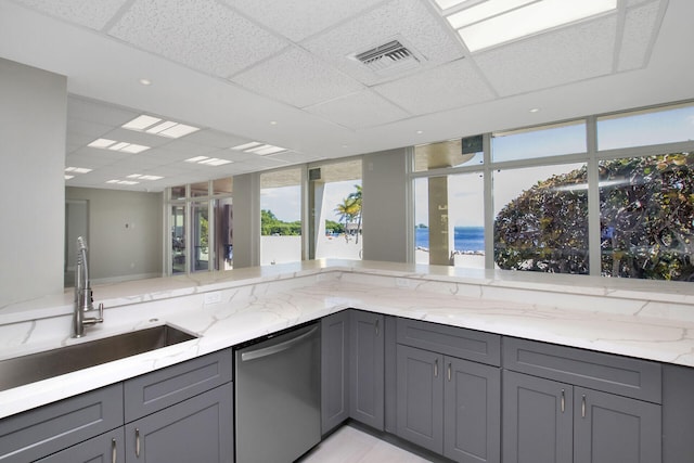 kitchen featuring gray cabinets, dishwasher, sink, light stone countertops, and a water view