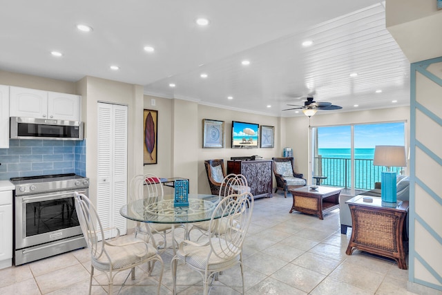 tiled dining room with a water view, ceiling fan, and ornamental molding