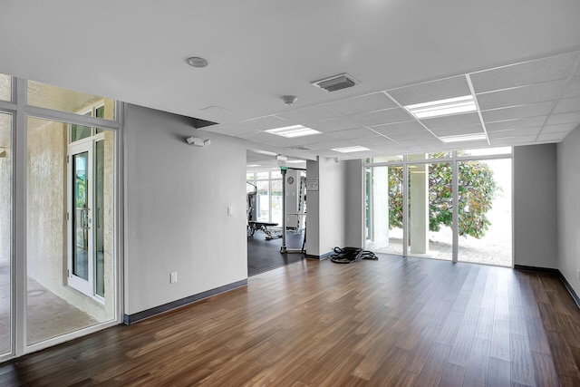 exercise room with a drop ceiling, dark wood-type flooring, and expansive windows