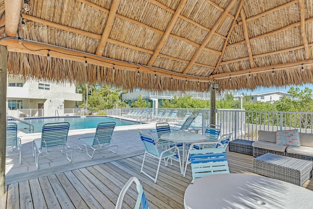 wooden terrace featuring a gazebo, outdoor lounge area, and a community pool