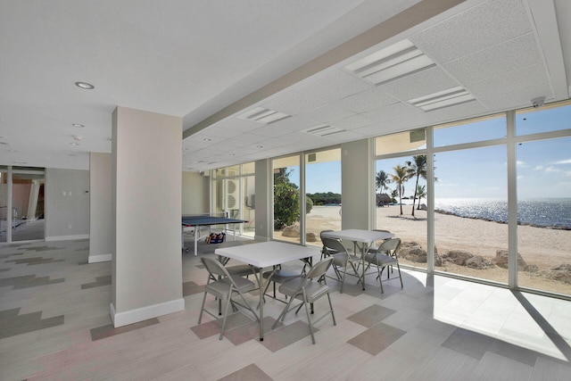 sunroom / solarium featuring a drop ceiling, a beach view, and a water view