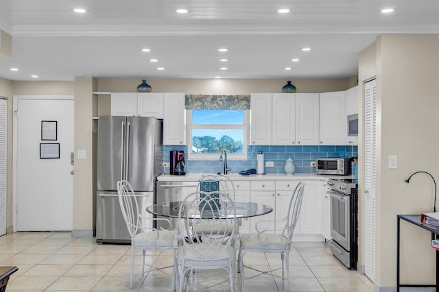 kitchen with light tile patterned flooring, high quality appliances, backsplash, and white cabinets