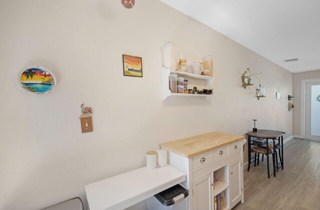 hall featuring light wood finished floors, visible vents, and baseboards