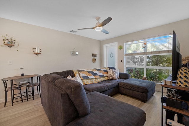 living room with visible vents, baseboards, light wood-style floors, and ceiling fan