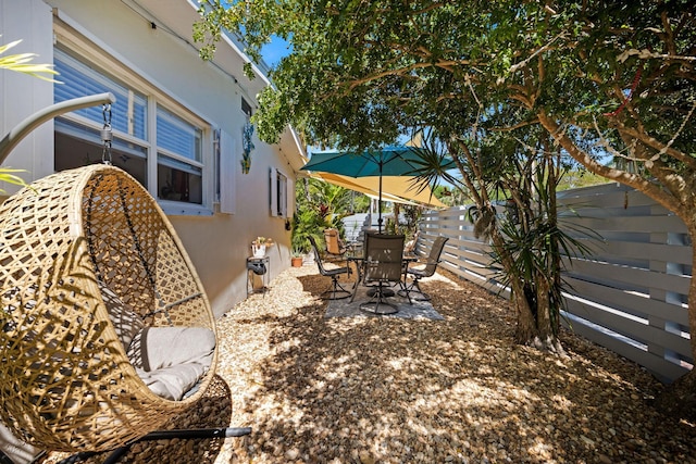 view of yard featuring a patio area, outdoor dining area, and fence