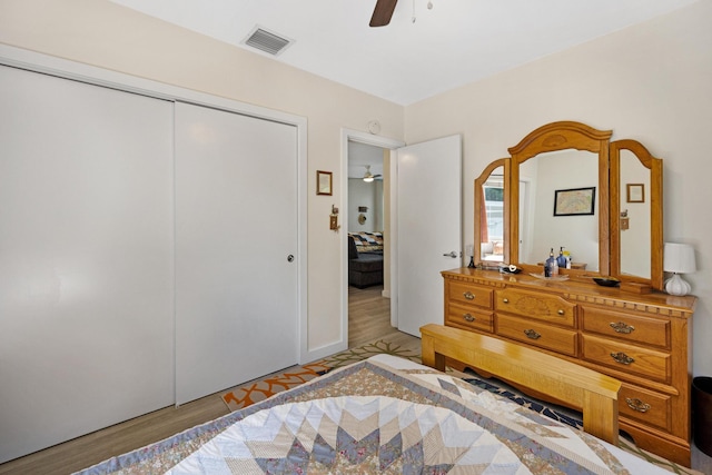 bedroom with light wood-type flooring, visible vents, a closet, and a ceiling fan