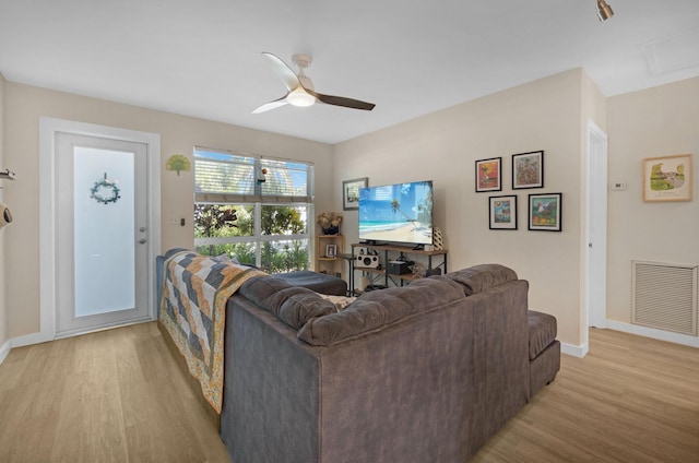 living room featuring visible vents, baseboards, a ceiling fan, and light wood finished floors