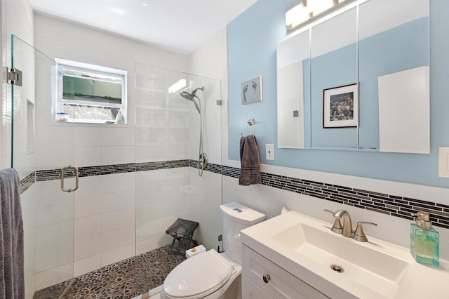 bathroom featuring toilet, tile walls, a stall shower, and vanity