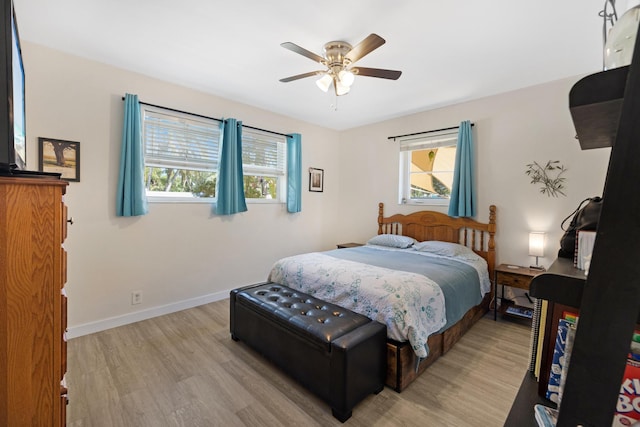 bedroom featuring baseboards, multiple windows, ceiling fan, and light wood finished floors