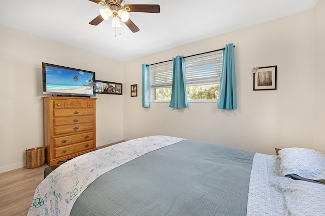 bedroom with a ceiling fan, wood finished floors, and baseboards