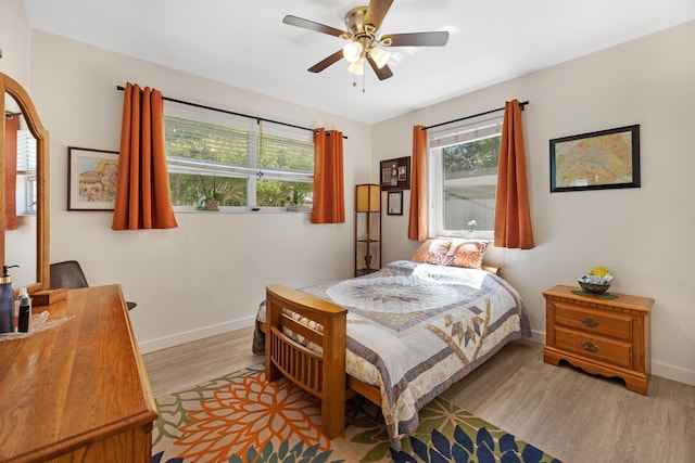 bedroom with light wood-type flooring, baseboards, and ceiling fan