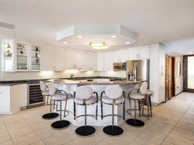 101 E Ocean Dr Unit C304, Key Colony, FL 33051 - kitchen with white cabinetry, a kitchen island, stainless steel appliances, wine cooler, and a kitchen bar