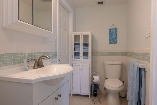 bathroom with vanity, tile walls, tile patterned floors, and toilet