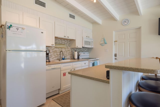 kitchen with sink, white appliances, a breakfast bar, backsplash, and white cabinets