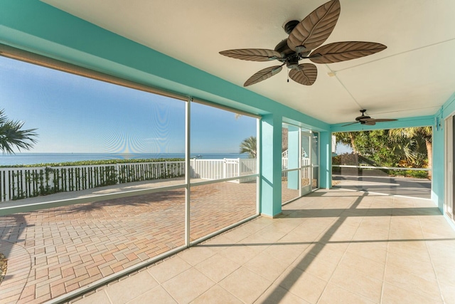 unfurnished sunroom featuring a water view, ceiling fan, and a healthy amount of sunlight