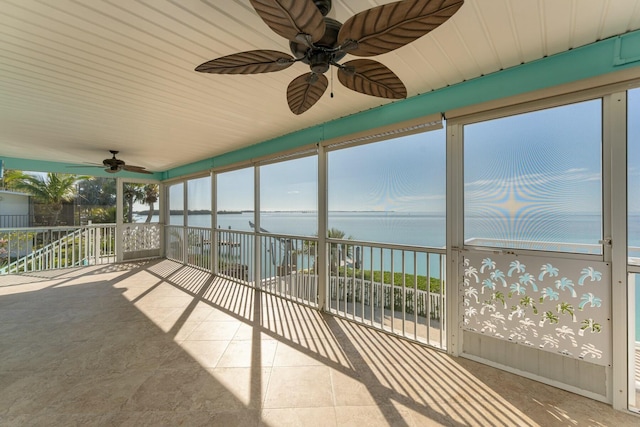 unfurnished sunroom with ceiling fan and a water view