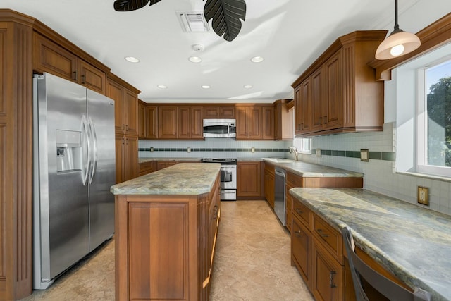 kitchen featuring stainless steel appliances, a center island, hanging light fixtures, and plenty of natural light