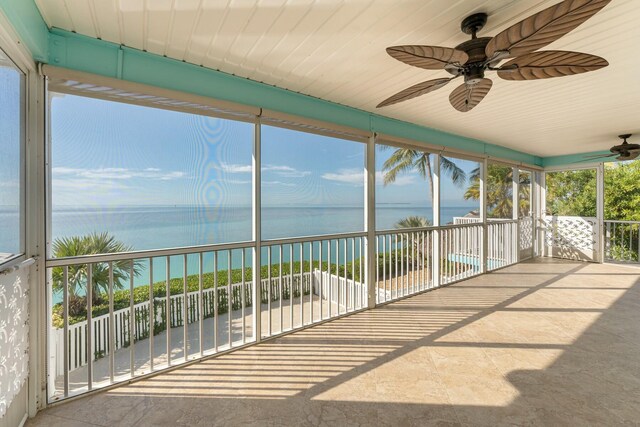 unfurnished sunroom with a water view and ceiling fan