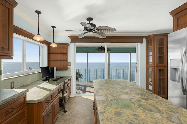 kitchen with pendant lighting, crown molding, stainless steel refrigerator with ice dispenser, tasteful backsplash, and light stone countertops