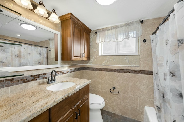 bathroom with vanity, toilet, and tile walls