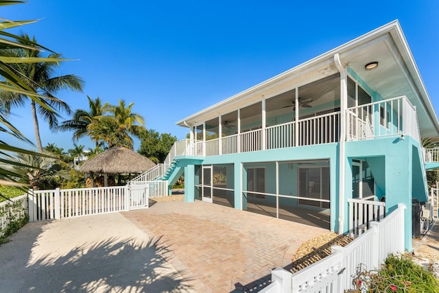 rear view of property featuring a gazebo, a sunroom, and ceiling fan