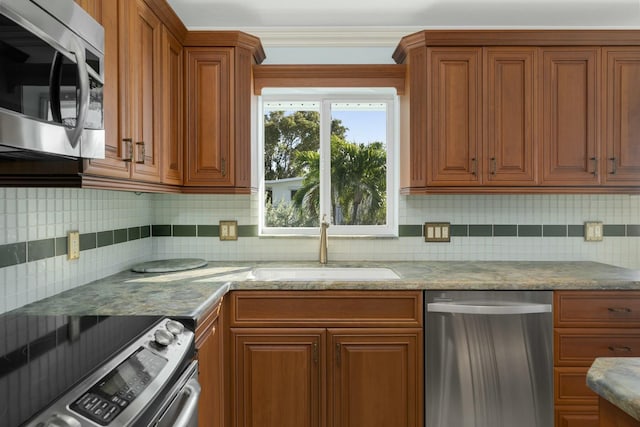 kitchen with tasteful backsplash, appliances with stainless steel finishes, sink, and light stone counters