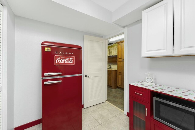 kitchen featuring white cabinetry, fridge, and light tile patterned flooring