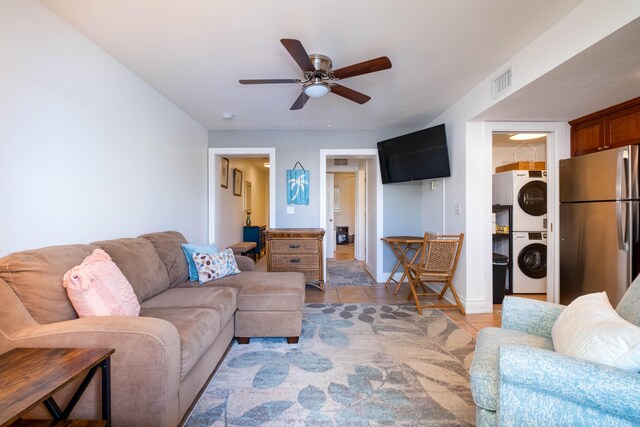 tiled living room with ceiling fan and stacked washing maching and dryer