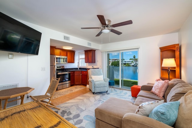 living room featuring sink, ceiling fan, and a water view