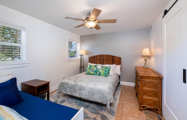 bedroom featuring tile patterned flooring, a barn door, and ceiling fan