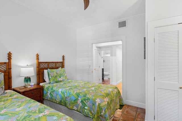 tiled bedroom featuring crown molding, ensuite bath, baseboards, a ceiling fan, and a closet