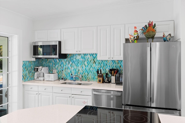 kitchen with tasteful backsplash, sink, white cabinets, stainless steel appliances, and crown molding