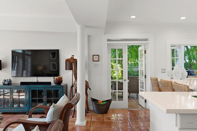 tiled living room with french doors, plenty of natural light, crown molding, and decorative columns