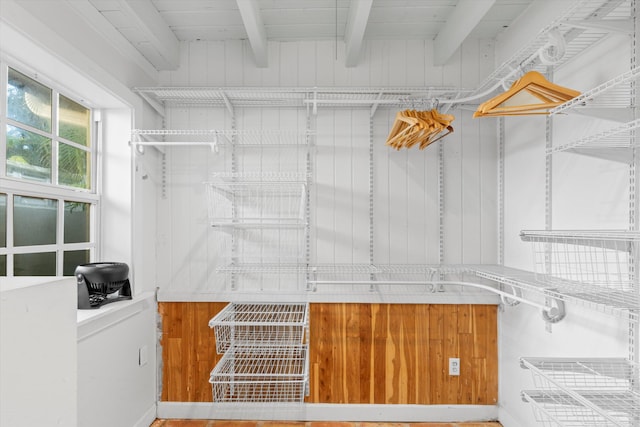 walk in closet featuring beamed ceiling and wood finished floors
