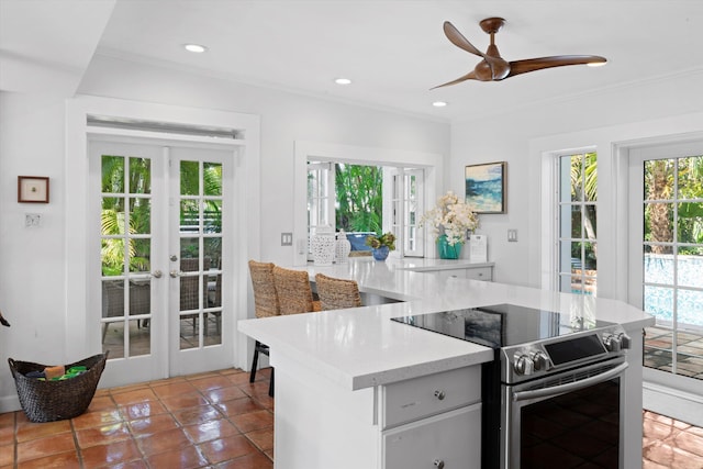 kitchen with crown molding, stainless steel range with electric cooktop, french doors, and dark tile patterned floors