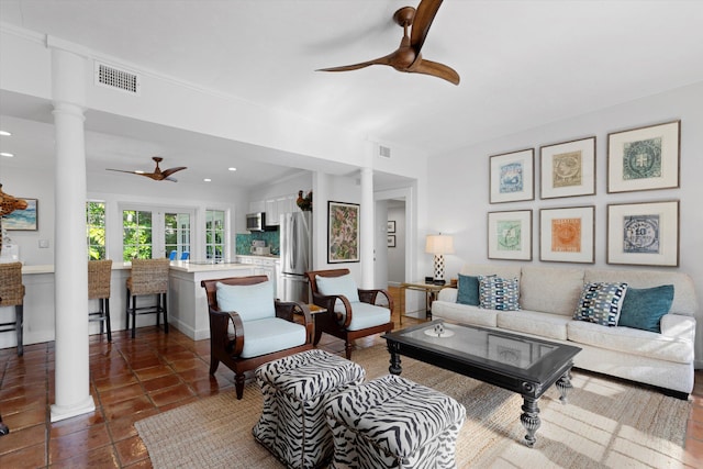 living room featuring ceiling fan, dark tile patterned flooring, and decorative columns