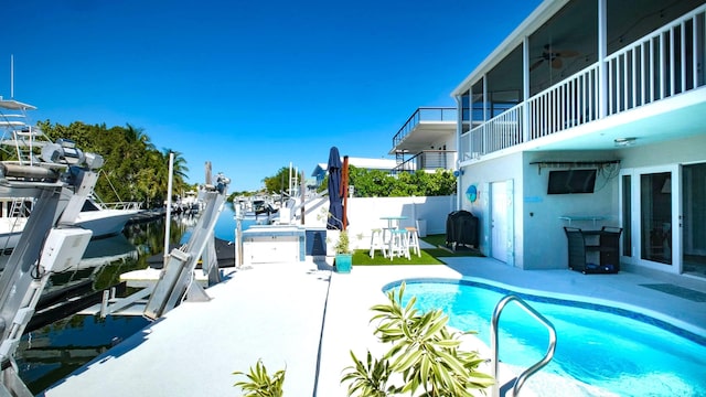 view of swimming pool with ceiling fan, a dock, and a patio area